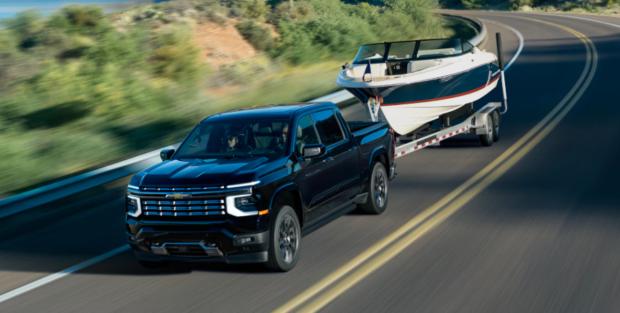 2027 Chevy Silverado towing boat on winding road